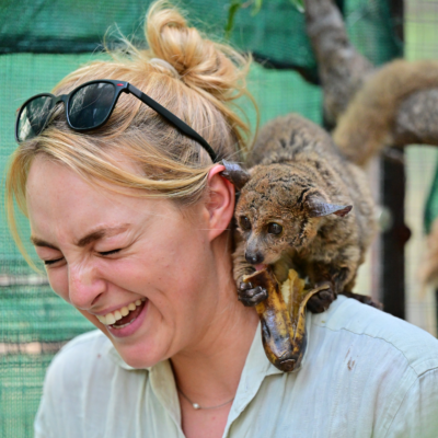 Wildlife volunteer smiling while feeding a bush baby during conservation work